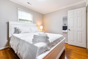 グリーンズボロにあるSouthern Charm 2BR Greensboro Nestの白いベッドルーム(タオル付きの白いベッド付)