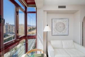 een woonkamer met een witte bank en een groot raam bij OLD TOWN - Cultural Experience in Málaga