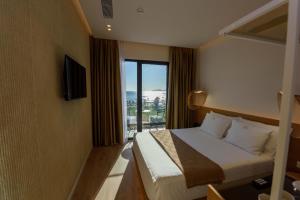 a hotel room with a bed and a large window at Mahoro Boutique Hotel in Vlorë