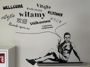 Un hombre sentado en una computadora portátil con palabras en una pared. en Mololo Art Hostel, en Sopot