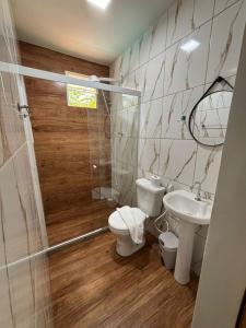 a bathroom with a toilet and a sink and a shower at Pousada Costa do Sol in Maricá