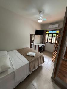a bedroom with a bed and a table and a window at Pousada Costa do Sol in Maricá