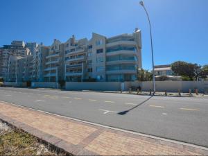 an empty street in front of a large building at Cape Town Beachfront Accommodation in Blouberg in Bloubergstrand