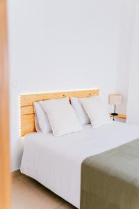 a bedroom with a bed with white sheets and pillows at Green House in Baleal