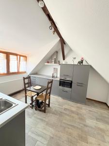 an attic kitchen with a table and chairs and a sink at Gîtes Hassenforder in Kaysersberg
