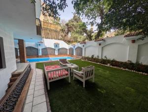 a yard with two benches and a table and a pool at A private room by the rooftop in Cairo
