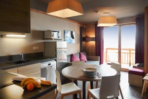 a kitchen and dining room with a table and a dining room at CGH Résidences & Spas les Chalets du Soleil Contemporain in Les Menuires +31 photos