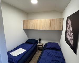 a small room with two beds and a cabinet at Enkhuizer Strand Chalet Meereszauber Nr 304 in Enkhuizen