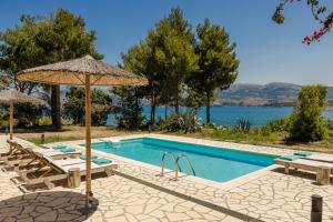 a swimming pool with umbrellas and chairs and a swimming pool at Villa Ostria in Lixouri