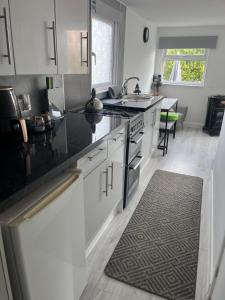 リーズダウン・オン・シーにあるBeachy Vibes and Chill Times 2 bed chalet in Leysdownの白いキャビネットと黒いカウンタートップを備えたキッチン