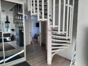 a white staircase in a living room with a mirror at Villa Tarvas by Hilla Villas in Rovaniemi