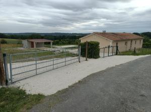 a fence in front of a house next to a road at maison de vacance montignac le coq in Montignac-le-Coq