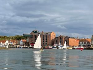 a group of sailboats on the water near a city at old coastguards station in Wells next the Sea
