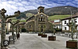 an old stone building with a clock tower in a town at Casa Pilar Casa Llara, En el paraíso, cerca de todo in Ujo