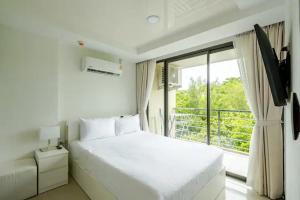 Un dormitorio blanco con una cama grande y una ventana. en Room 402 Rawai Beach Condo, en Nai Harn Beach 8 fotos más