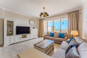 a living room with a couch and a tv at Spacious Ocean View Family Townhouse in Puerto de Santiago