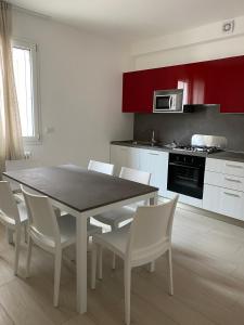 a kitchen with a dining room table and white chairs at Le Casine di Cervia in Cervia