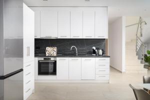 a kitchen with white cabinets and black appliances at Petrus Luxury Villas in Old Hersonissos - 3 Bedrooms & 3 Bathrooms in Hersonissos