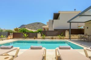 a swimming pool with chairs and a house at Petrus Luxury Villas in Old Hersonissos - 3 Bedrooms & 3 Bathrooms in Hersonissos