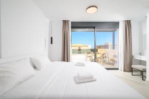 a white bedroom with a large bed and a balcony at Petrus Luxury Villas in Old Hersonissos - 3 Bedrooms & 3 Bathrooms in Hersonissos +118 photos