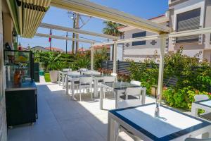 a patio with white tables and white chairs at Anzede Konaklama Çeşme in Çeşme