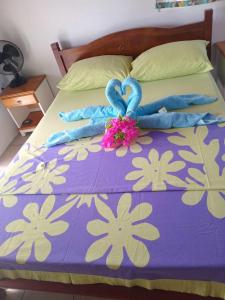 a bed with a purple and white comforter with two blue gloves at Vaimoe Lodge à Rangiroa sur Tiputa in Tiputa