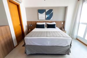 a bedroom with a large white bed with blue pillows at Confortável Flat em Brasília-BR in Brasília