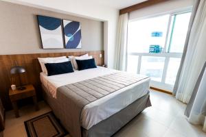 a bedroom with a large bed and a large window at Confortável Flat em Brasília-BR in Brasília