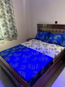 a bed with a blue comforter and pillows on it at Tapoko residence in Yaoundé