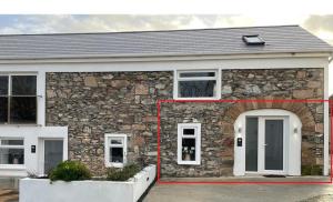 a stone house with a red line around the door at Merok Mill House & Old Granary in Six Road Ends