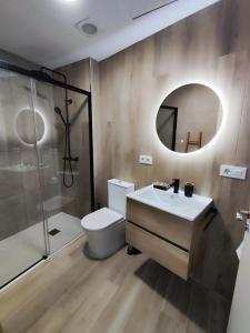 een badkamer met een wastafel, een toilet en een spiegel bij Apartamento Río Turia C in Valencia