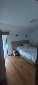 a bedroom with a white bed and a wooden floor at Peace & green in Žabljak +4 photos