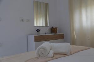 Una habitación blanca con una cama con toallas. en Devido Holiday, en Durrës