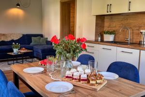 a dining room table with food and red flowers on it at Beskidzki Zakątek Ustroń - Przytulny domek z kominkiem, idealny na relaks i ucieczkę od miasta in Ustroń