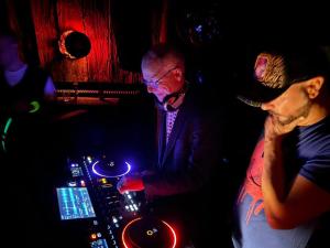 a man and a woman standing in a bar with a dj at Mondschein Hotel & Chalet Ski-In Ski-Out Luxus am Arlberg in Stuben am Arlberg
