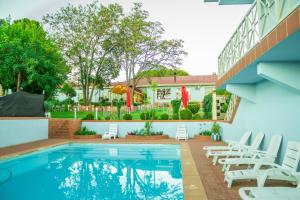 a swimming pool with chairs and a building at Blue Mountain Inn Lesotho in Teyateyaneng