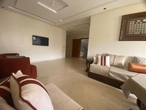 a living room with a couch and a tv on the wall at Appartement spatieux in Tangier