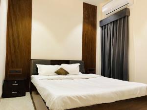 a bedroom with a bed with white sheets and a window at The Divine Villa ! in Indore