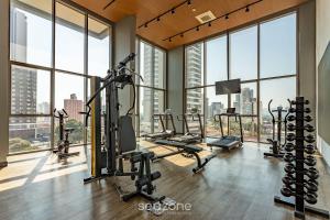 a gym with cardio equipment and large windows at HMO - Estúdios completos em prédio c/ piscina in Sao Paulo