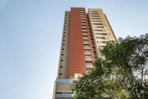 a tall apartment building with a red at HMO - Estúdios completos em prédio c/ piscina in Sao Paulo