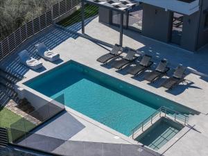an overhead view of a swimming pool with lounge chairs at Heliodora Villa, Premium Nature Living, By ThinkVilla in Áyios Mámas