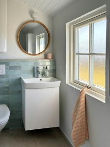 a bathroom with a white sink and a mirror at Bright And Charming Summer House Near Løkken in Løkken