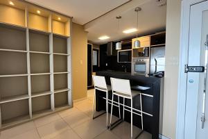 a kitchen with a black counter and white chairs at Apto 2 suítes - Umarizal in Curro Velho +17 photos