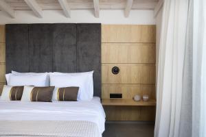 a bedroom with a bed with white sheets and pillows at Heliodora Villa, Premium Nature Living, By ThinkVilla in Áyios Mámas