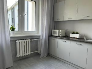 a kitchen with white cabinets and a window at Apartament Piastowska in Gliwice