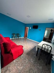 a living room with a red couch and a blue wall at Quarto Triplo Solteiro in Barueri