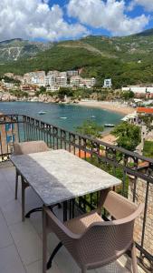 a table and chairs on a balcony overlooking a beach at Apartments Mitrovići Miločer in Sveti Stefan