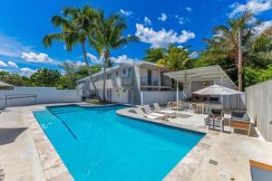 a swimming pool in front of a house with palm trees at Viento Beach Lodge in Dorado