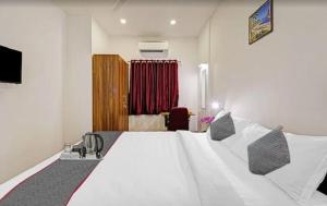 a bedroom with a large white bed and a red curtain at Super Townhouse OAK YMCA Ground in Chennai