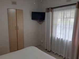 a bedroom with a bed and a tv and a window at Faraaz BnB in Ladysmith